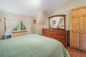 Een slaapkamer met een bed, een dressoir en een grote spiegel.