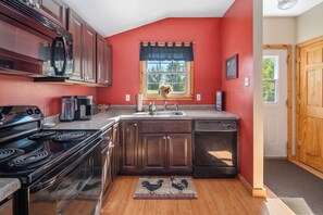 Cozinha com parede vermelha, janela com vista e placa de boas-vindas.