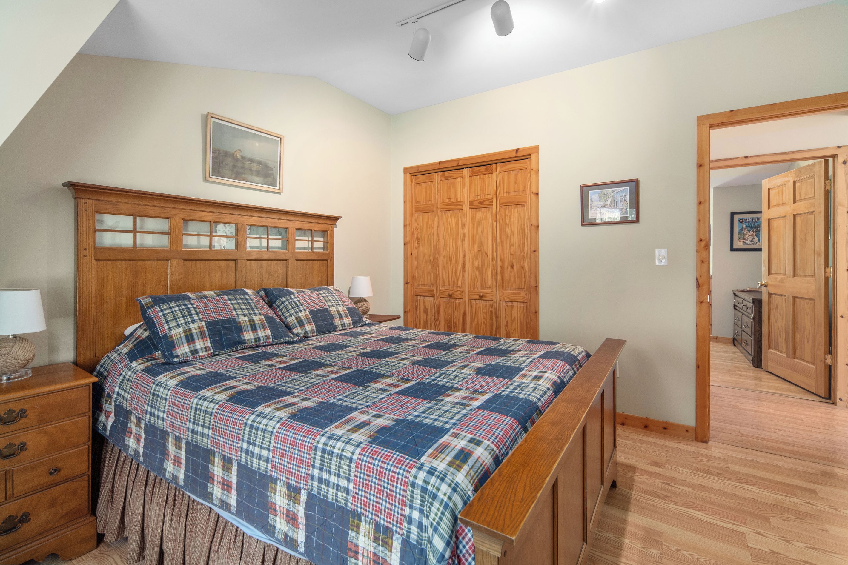 Un dormitorio con una cama grande, un armario de madera y una puerta que da a otra habitación.