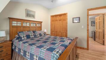 Une chambre avec un grand lit, une armoire en bois et une porte donnant sur une autre pièce.