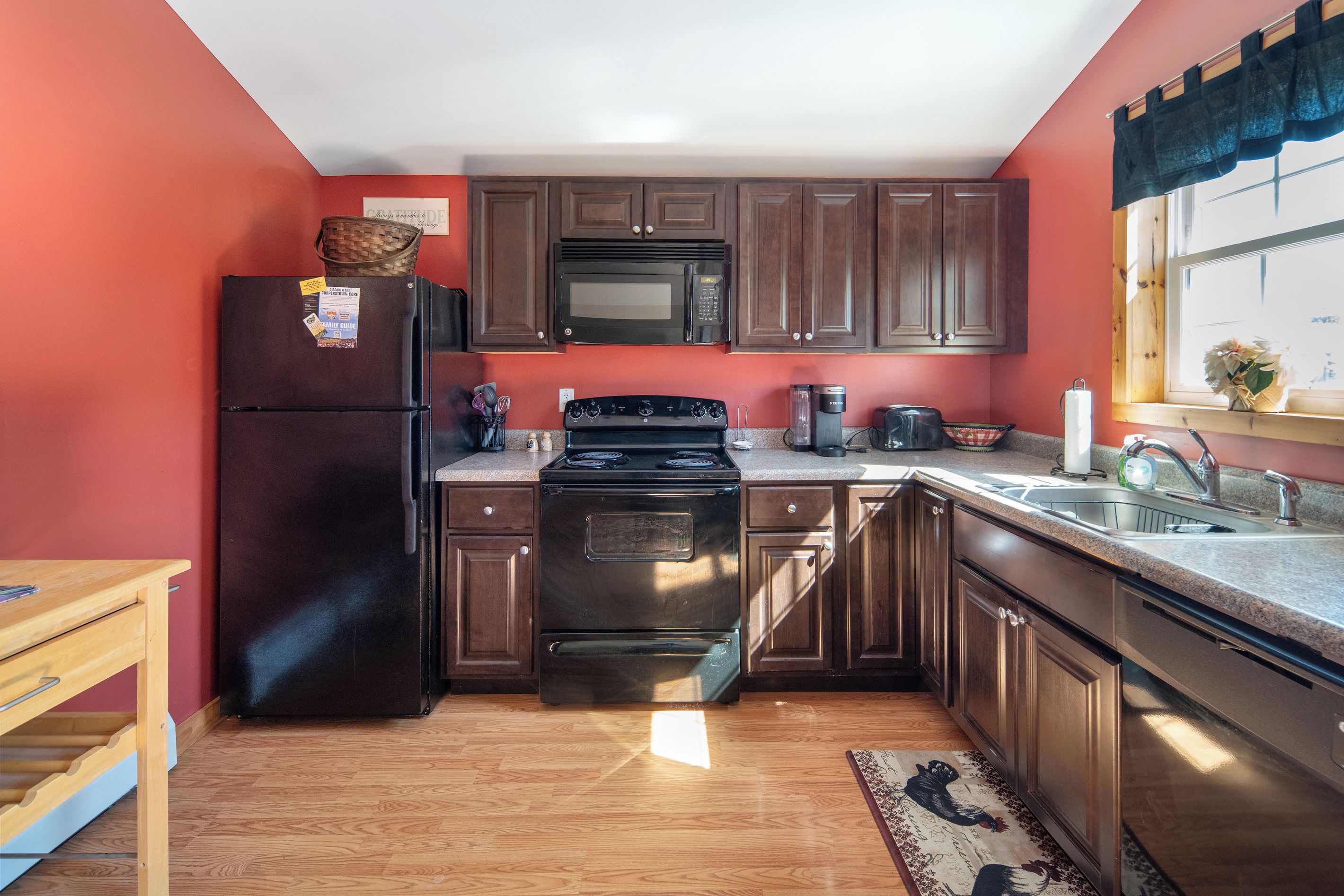 A compact kitchen with a refrigerator, microwave, stove, and sink.