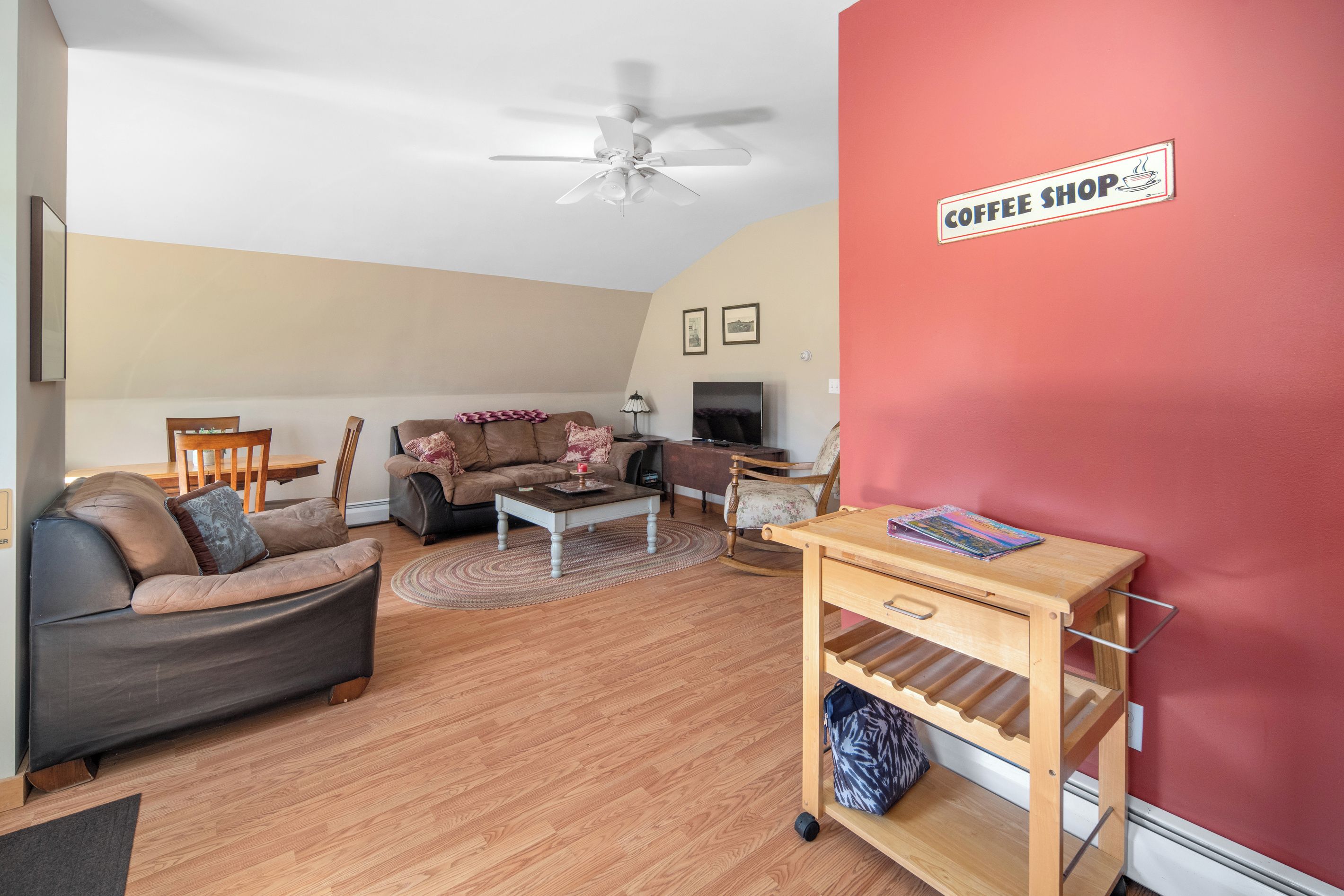 A living room with a sofa, coffee table, and a coffee shop sign on the wall.