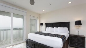 Een slaapkamer met een groot bed, een nachtkastje, twee wandlampen en een schuifdeur naar een balkon.