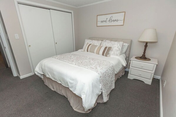 A bedroom with a bed, nightstand, and a wall-mounted lamp.