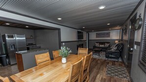 A compact kitchen with a refrigerator, stove, and sink. There is a dining area with a wooden table and chairs, and a living area with a couch and a coffee table. - Rockhouse Cabin — Front Row View to Rock Formations (Rockbridge)