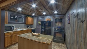 A kitchen with wooden cabinets, granite countertops, a central island, and stainless steel appliances. - Rockhouse Cabin — Front Row View to Rock Formations (Rockbridge)