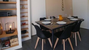 Un espace repas moderne avec une table en bois dressée pour quatre personnes, des chaises noires et un mur blanc orné d’un motif circulaire décoratif.