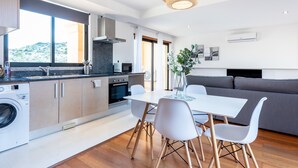 A modern kitchen with a dining area, built-in appliances, and a large window.