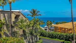 A coastal residential area with palm trees, a curved road, and a view of the ocean. - Maui Kamaole #L-203 Full Ocean View, A/C Throughout, Wifi, Great Location (Kihei)