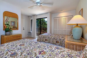 A bedroom with two beds, a ceiling fan, a large mirror, a potted plant, and a view of the outdoors.