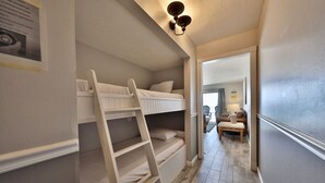 En smal hall med en våningssäng, en stege och en liten sittgrupp med ett bord och stolar.