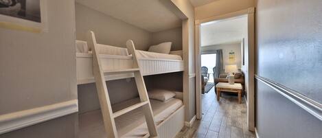 A narrow hallway with a bunk bed, a ladder, and a small seating area with a table and chairs.