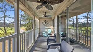 A covered porch with a ceiling fan, wicker furniture, and a view of the surrounding landscape. - TB 19E Eagle's Nest Beautiful three bedroom condo located in True Blue (PAWLEYS ISLAND)