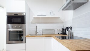 Una cocina moderna con electrodomésticos de acero inoxidable, encimera de madera y armarios blancos.