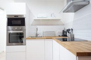 A modern kitchen with stainless steel appliances, a wooden countertop, and white cabinetry.