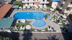 Relax by the rectangular pool surrounded by lush greenery and lounge chairs.