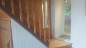 Eine Holztreppe führt zu einer Zwischenebene mit einer Tür und einem Fenster.
