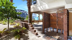 A covered outdoor area with a wooden door, steps leading to a building, and a palm tree. - Gulf view, three bedroom, two bath condo in Mexico Beach. (Mexico Beach)