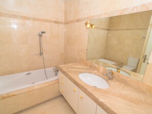 Een badkamer met een bad, wastafel en spiegel.