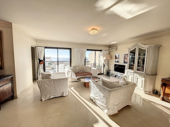 A spacious living room with a large window, a television, and a cabinet.