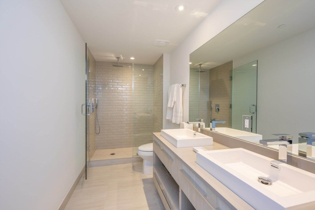 A modern bathroom with a glass-enclosed shower, two sinks, and a large mirror.
