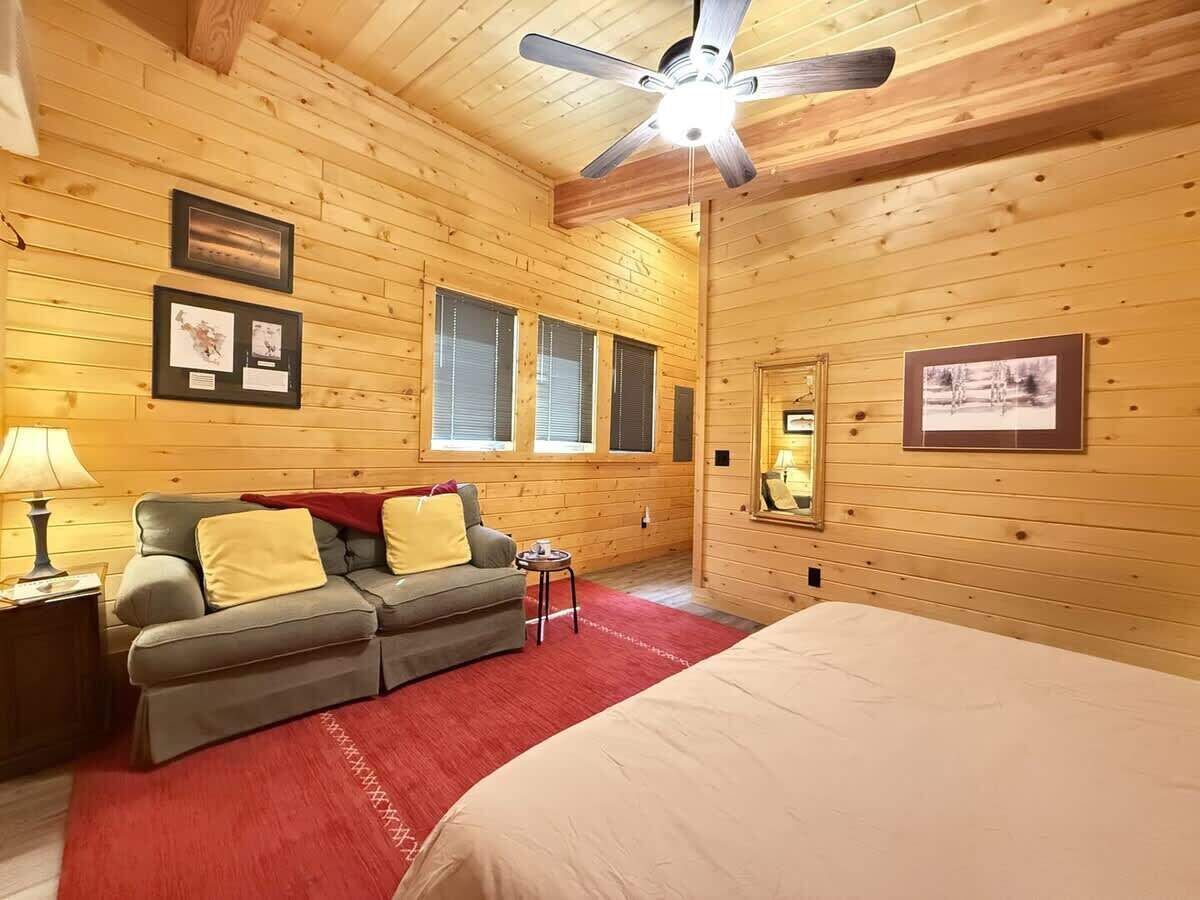 Ett mysigt rum med en säng, en soffa, ett litet bord och en takfläkt.