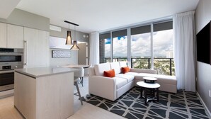 A modern living room with a sofa, coffee table, and a view of the city through large windows.