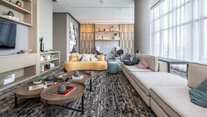 A modern living room with a sofa, armchairs, a coffee table, and a TV.