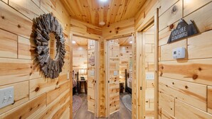 A wooden cabin interior with a circular mirror, a sign encouraging outdoor exploration, and a thermostat on the wall. - Beside Still Water 2 - 2 Bedrooms, 2 Baths, Sleeps 6 Home by RedAwning (Cosby)