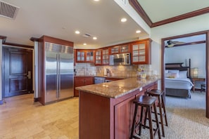Una cocina moderna con encimeras de granito, electrodomésticos de acero inoxidable y armarios de madera.