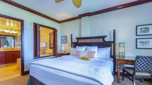 Un dormitorio espacioso con una cama grande, cabecera de madera y un rincón de descanso con una silla y una mesa.