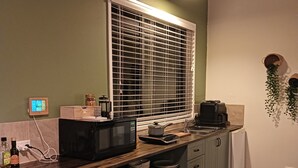 A compact kitchen with a microwave, coffee maker, and a window with blinds. - Moonlight Studio- Nannup's favourite accommodation.  (Nannup)