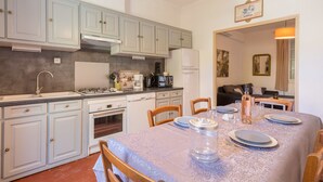 A kitchen with white cabinets, a dining table set with plates and glasses, and a coffee maker. - Le Mas, Provencal house between sea and vineyards (Hyères)