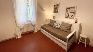 A small, cozy bedroom with a single bed, a window with sheer curtains, a radiator, and wall art. - Le Mas, Provencal house between sea and vineyards (Hyères)
