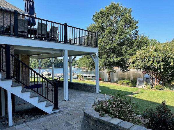 A two-story house with a covered patio, a staircase, and a view of a lake.