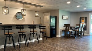 Een moderne keuken met een bar, houten vloer en moderne verlichtingsarmaturen.