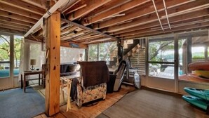 A rustic cabin interior with a wooden ceiling, a sofa, a dining table, and a view through large windows. - Welcome to DOCKTAILS - direct Bayfront - tropical private island - PRIVATE DOCK (Placida)