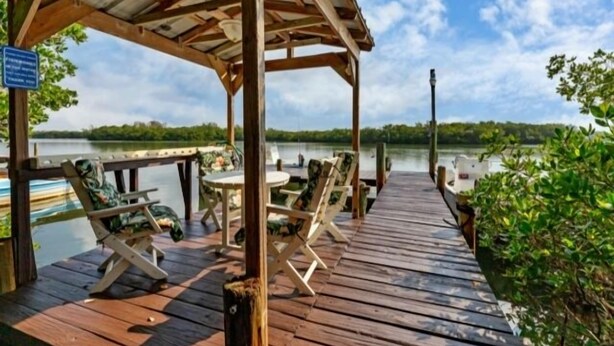 A wooden dock with lounge chairs and a covered seating area overlooking a calm lake. - Welcome to DOCKTAILS - direct Bayfront - tropical private island - PRIVATE DOCK (Placida)