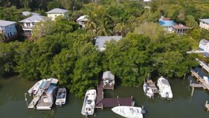 An aerial view of a residential area with houses, dense greenery, and a marina with several boats docked. - Welcome to DOCKTAILS - direct Bayfront - tropical private island - PRIVATE DOCK (Placida)