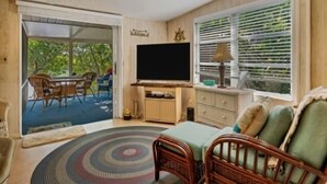 A room with a television, wicker furniture, a ceiling fan, and a view of greenery outside. - Welcome to DOCKTAILS - direct Bayfront - tropical private island - PRIVATE DOCK (Placida)
