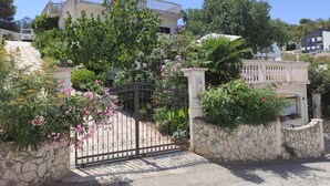 Un lotissement résidentiel fermé, délimité par un mur de pierre, une grille en métal et un immeuble doté d’un balcon.