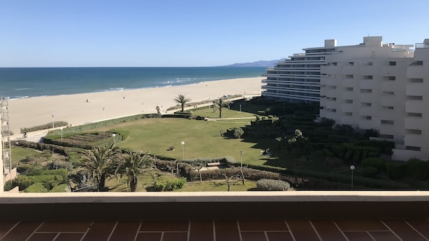 A view of a beach with a hotel in the background.