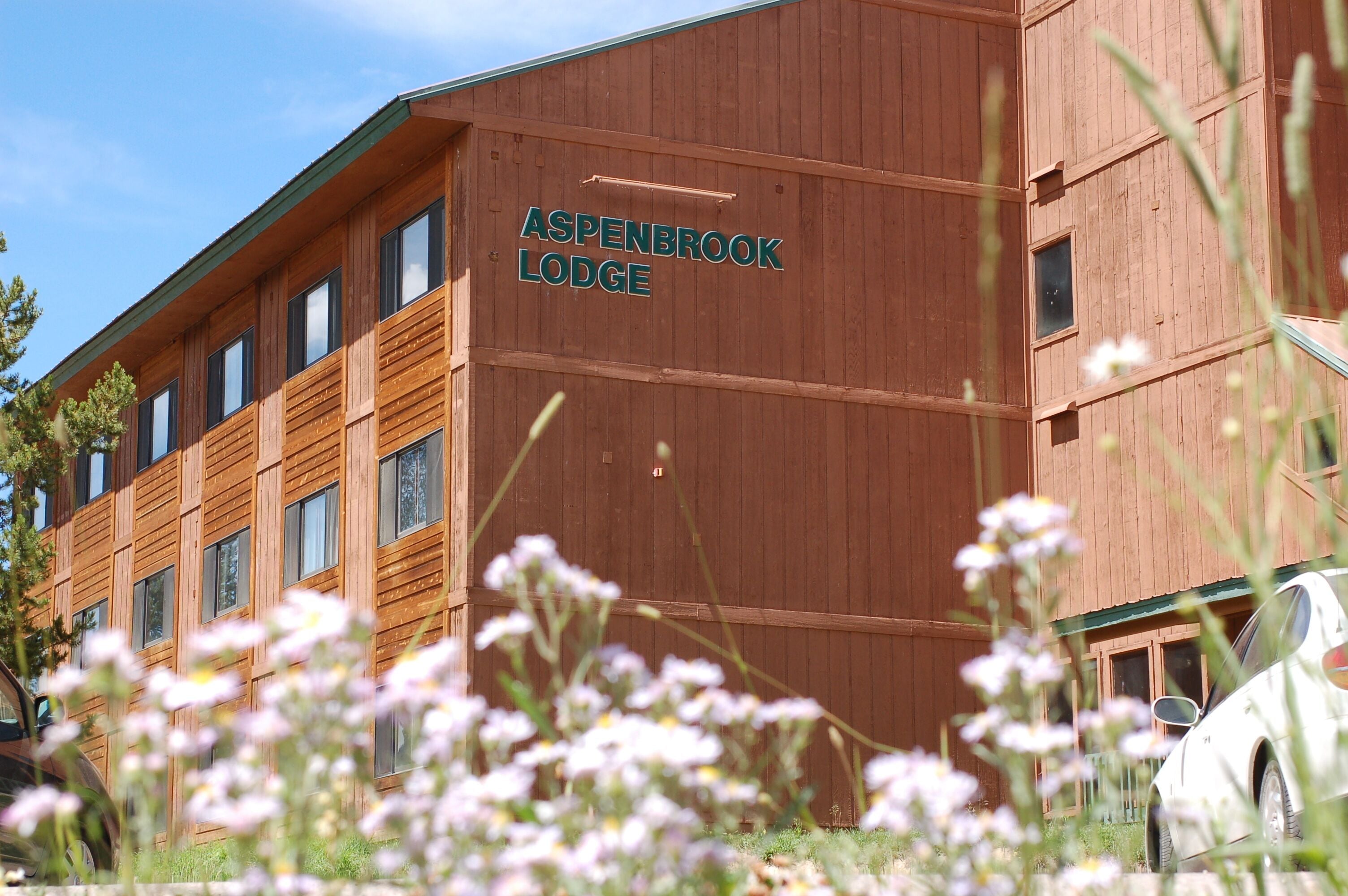 Un edificio de madera con el letrero "Aspenbrook Lodge" en su fachada.