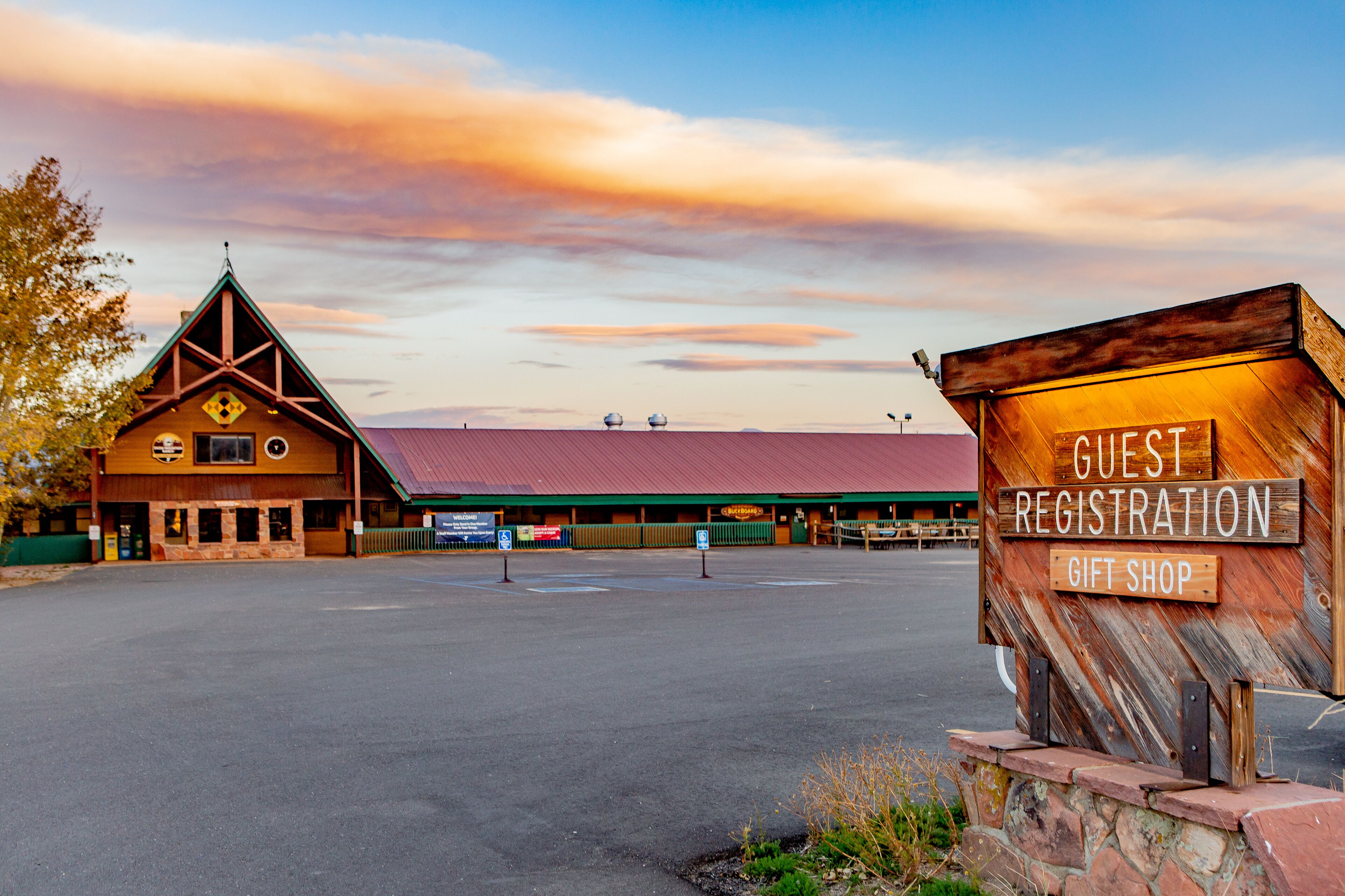 A guest registration area with a wooden signboard and a building with a red roof.
