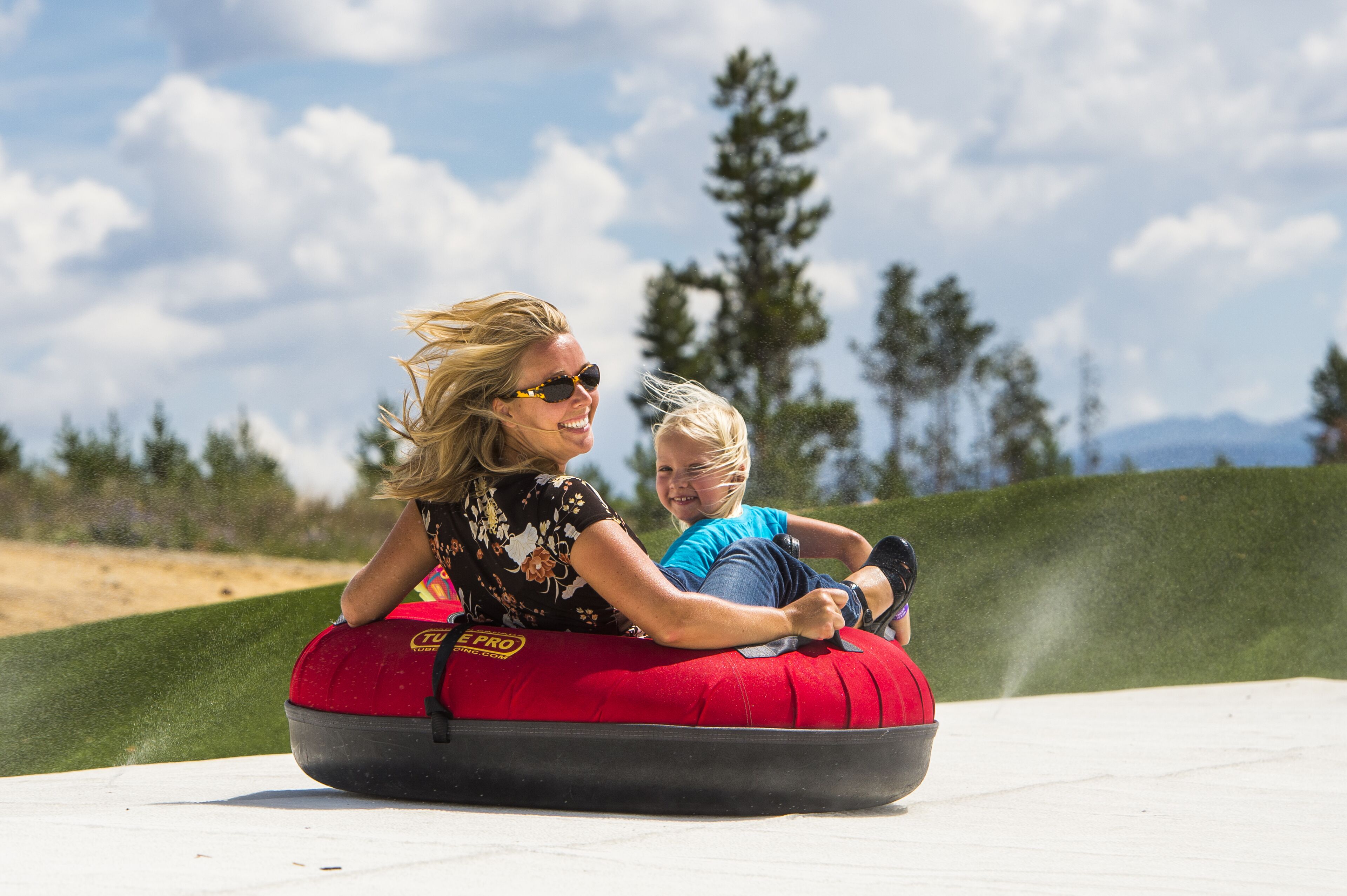 Une femme et un enfant sur une bouée gonflable rouge, dans un espace dédié aux activités de plein air.