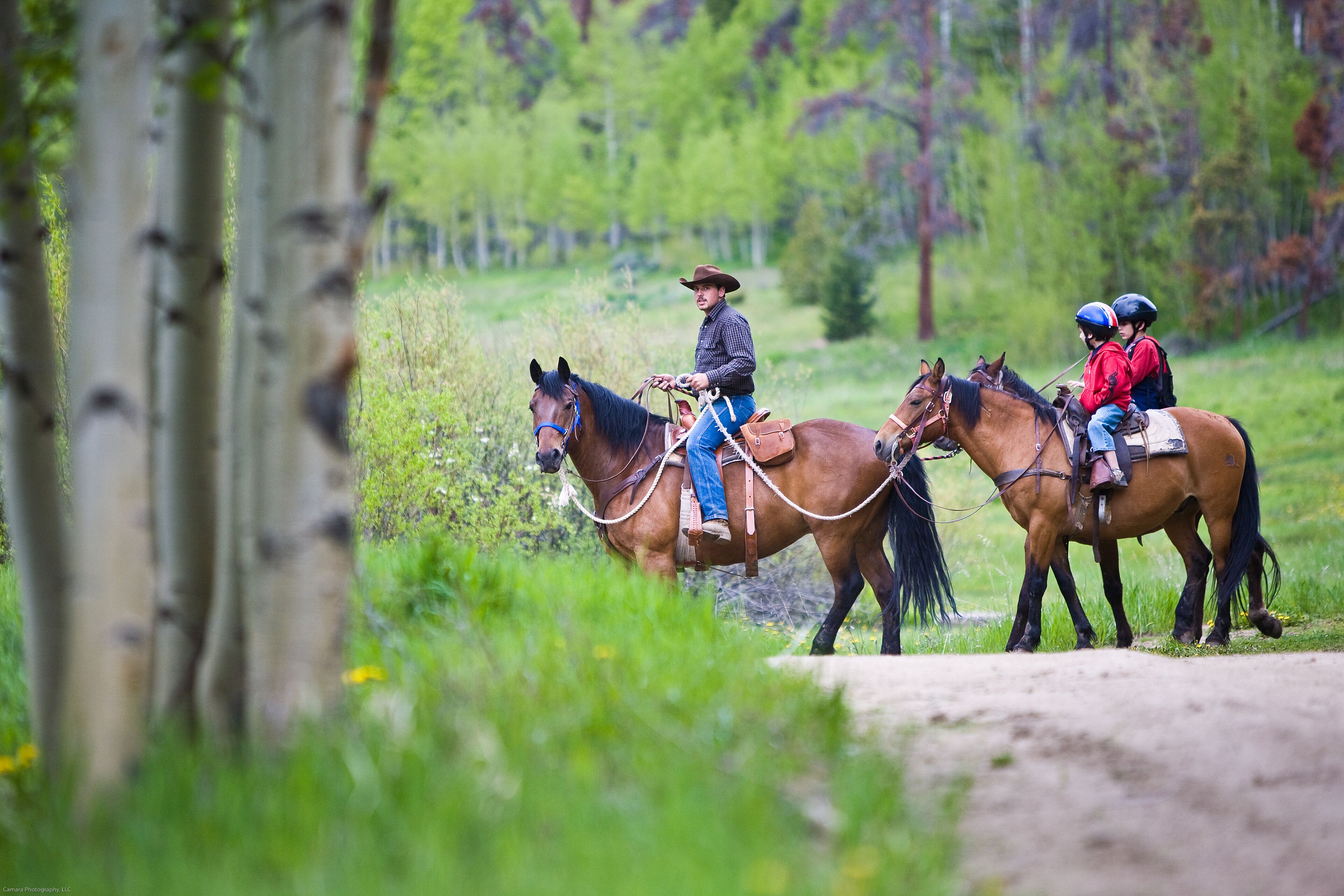 Un sendero de tierra con tres personas montando a caballo.