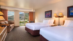 A hotel room with two beds, a desk, a chair, and a view of the outdoors. - YMCA of the Rockies Snow Mountain Ranch (Granby)