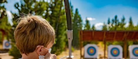 A person aiming a bow at targets.