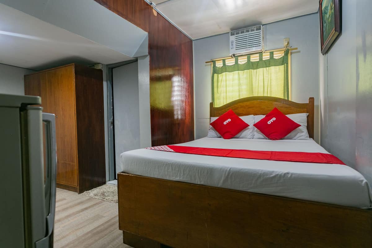 A bedroom with a wooden bed, white bedding, and red pillows.