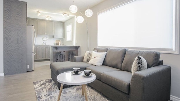 A modern living room with a grey sofa, a round coffee table, and a large window.
